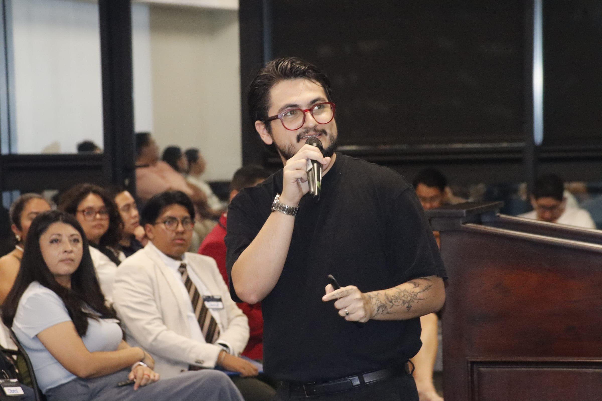 Marcello Sisniega presentando de pie ante una audiencia en un auditorio