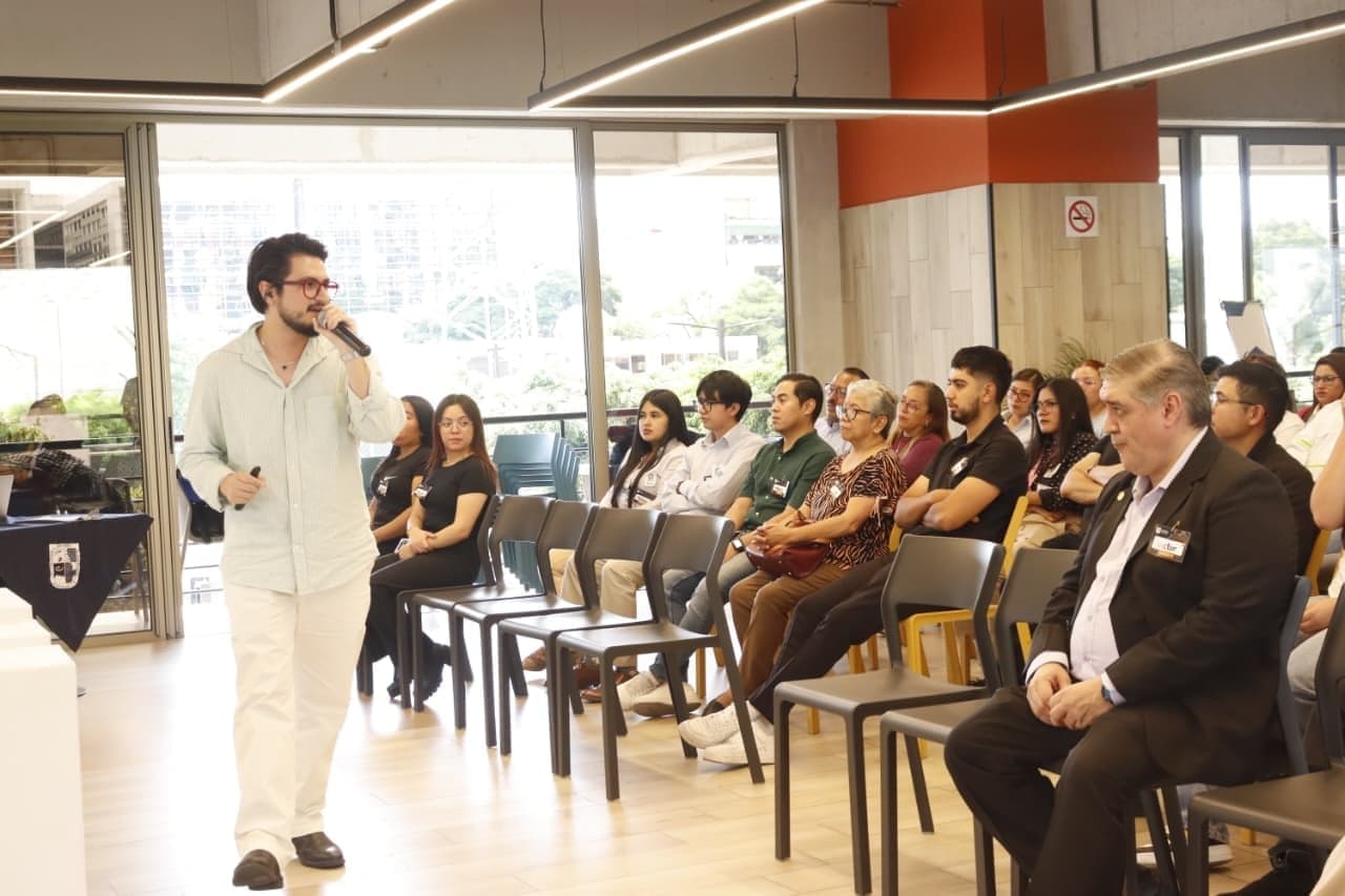 Marcello Sisniega facilitando un taller con micrófono frente a un grupo de participantes